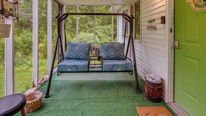 A porch with two swing seats, a wicker basket, and a green door. - Walk to Town: Fayetteville Retreat w/ Hot Tub! (Fayetteville)