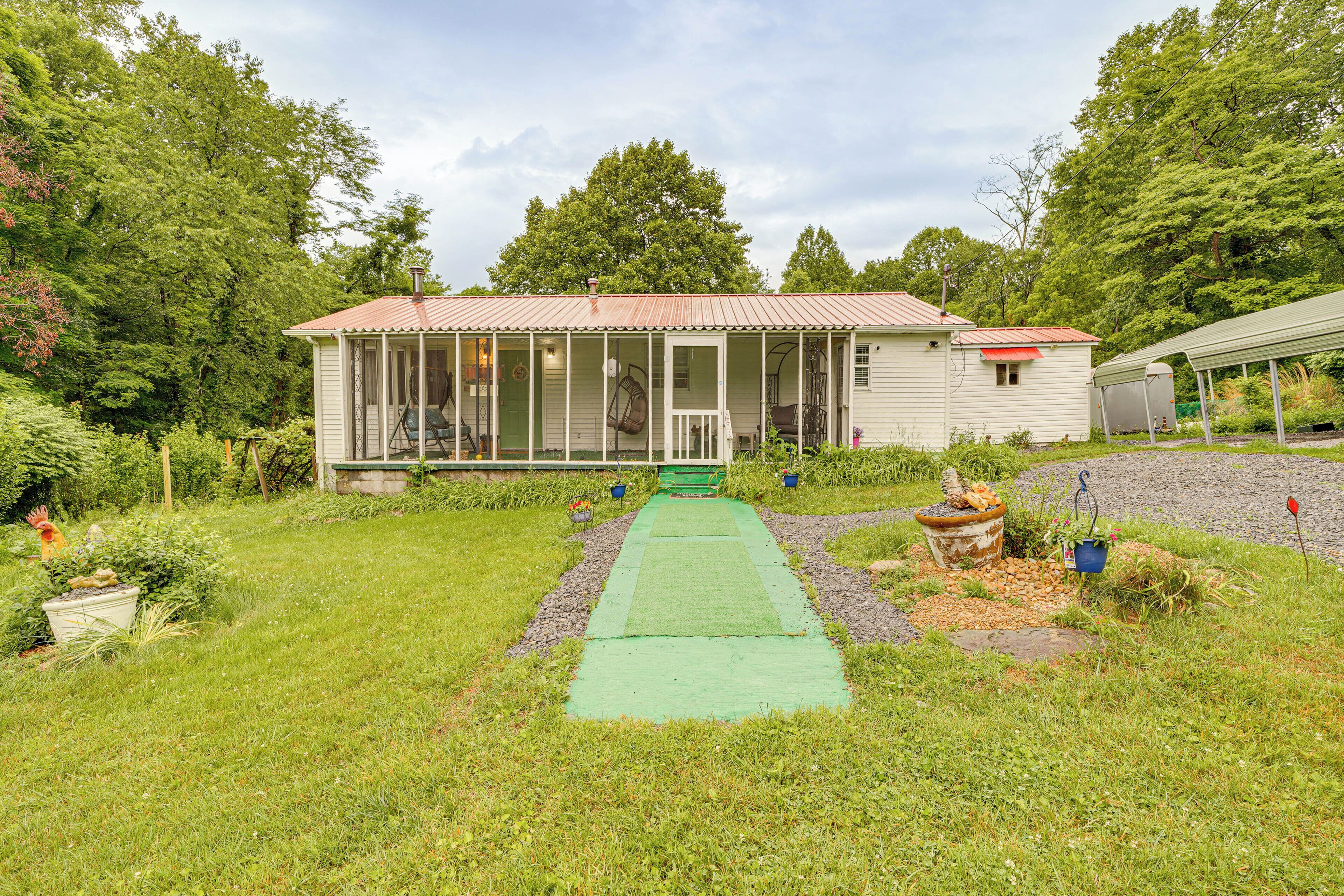 A house with a porch, a green pathway leading to the entrance, and a garden with potted plants.