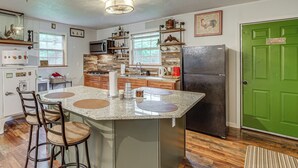 A kitchen with a central island, bar stools, a refrigerator, and a green door. - Walk to Town: Fayetteville Retreat w/ Hot Tub! (Fayetteville)