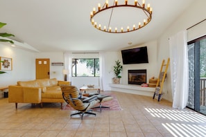 A living room with a sofa, a chair, a TV, a fireplace, and a large window.