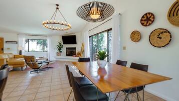 A modern dining area with a wooden table, black chairs, and two pendant lights.