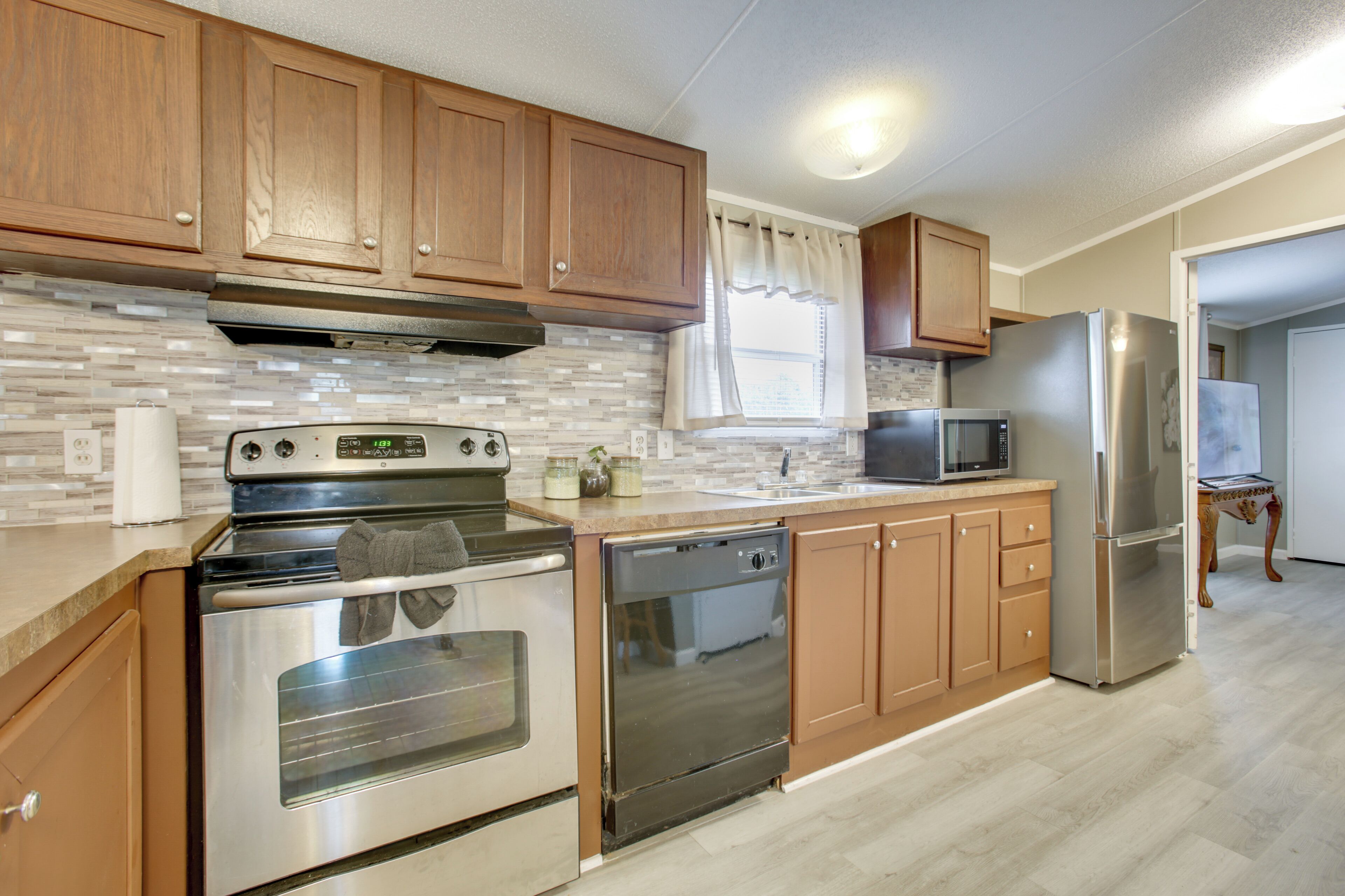 A kitchen with wooden cabinets, stainless steel appliances, a microwave, and a refrigerator.