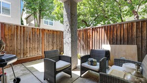 A patio area with wicker furniture, a barbecue grill, and a wooden fence. - Spacious + Pet-friendly Family Home in Tracy (Tracy)