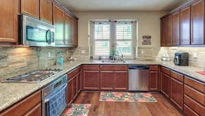 A kitchen with wooden cabinets, a stainless steel microwave, a gas stove, a dishwasher, and a granite countertop. - Spacious + Pet-friendly Family Home in Tracy (Tracy)
