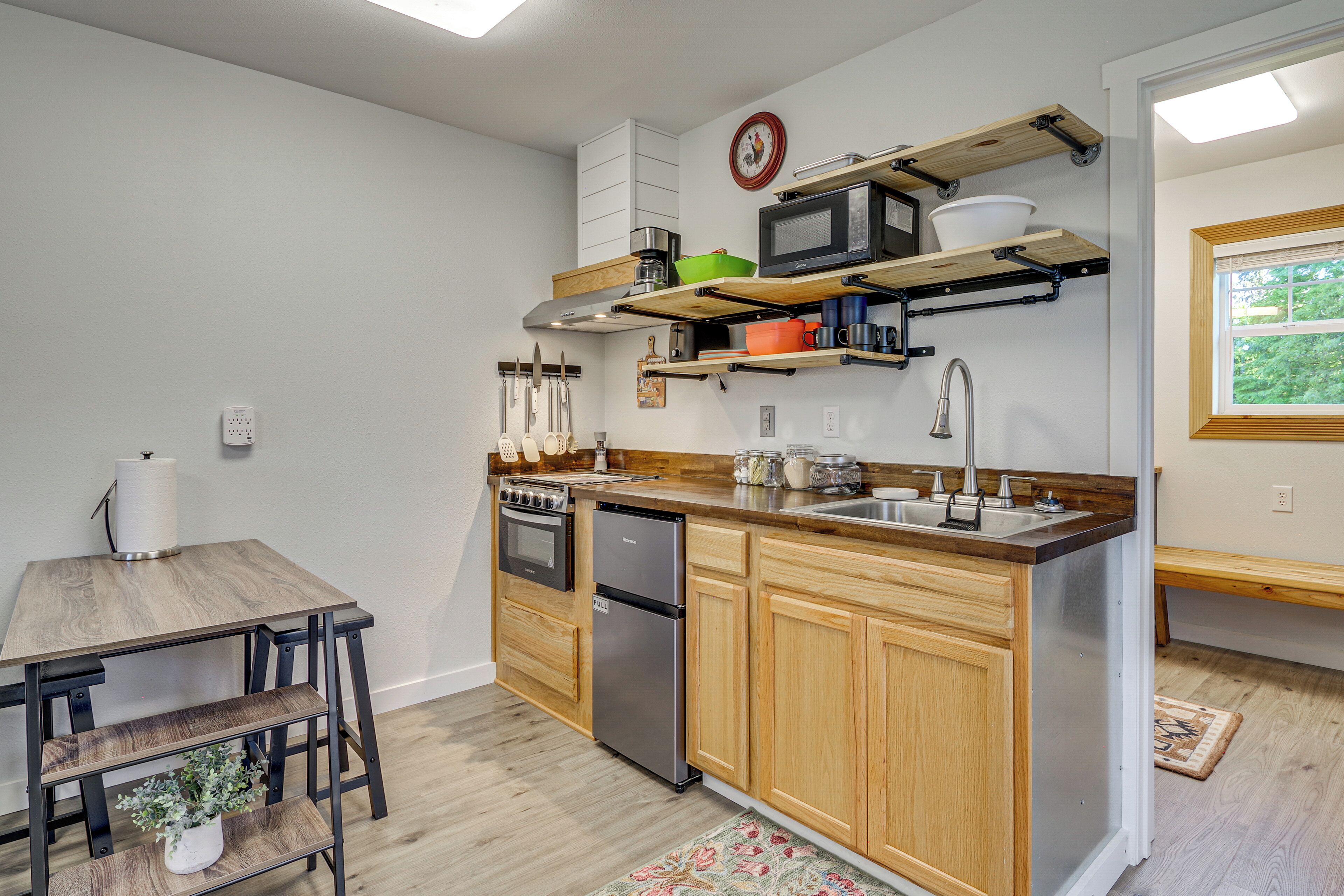 A compact kitchen with wooden cabinets, a built-in oven, a dishwasher, and a sink.
