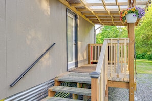 A wooden deck with a bench, a metal handrail, and a hanging flower pot.