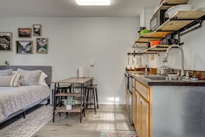 A compact bedroom with a bed, bedside table, and a small dining area.
