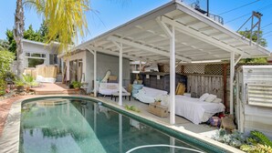 A covered outdoor swimming pool area with a patio, lounge chairs, and a bed. - Cozy Studio w/ Patio & Shared Pool in La Jolla! (La Jolla)