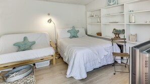 A bedroom with two beds, a desk, a television, and a shelf with decorative items. - Cozy Studio w/ Patio & Shared Pool in La Jolla! (La Jolla)