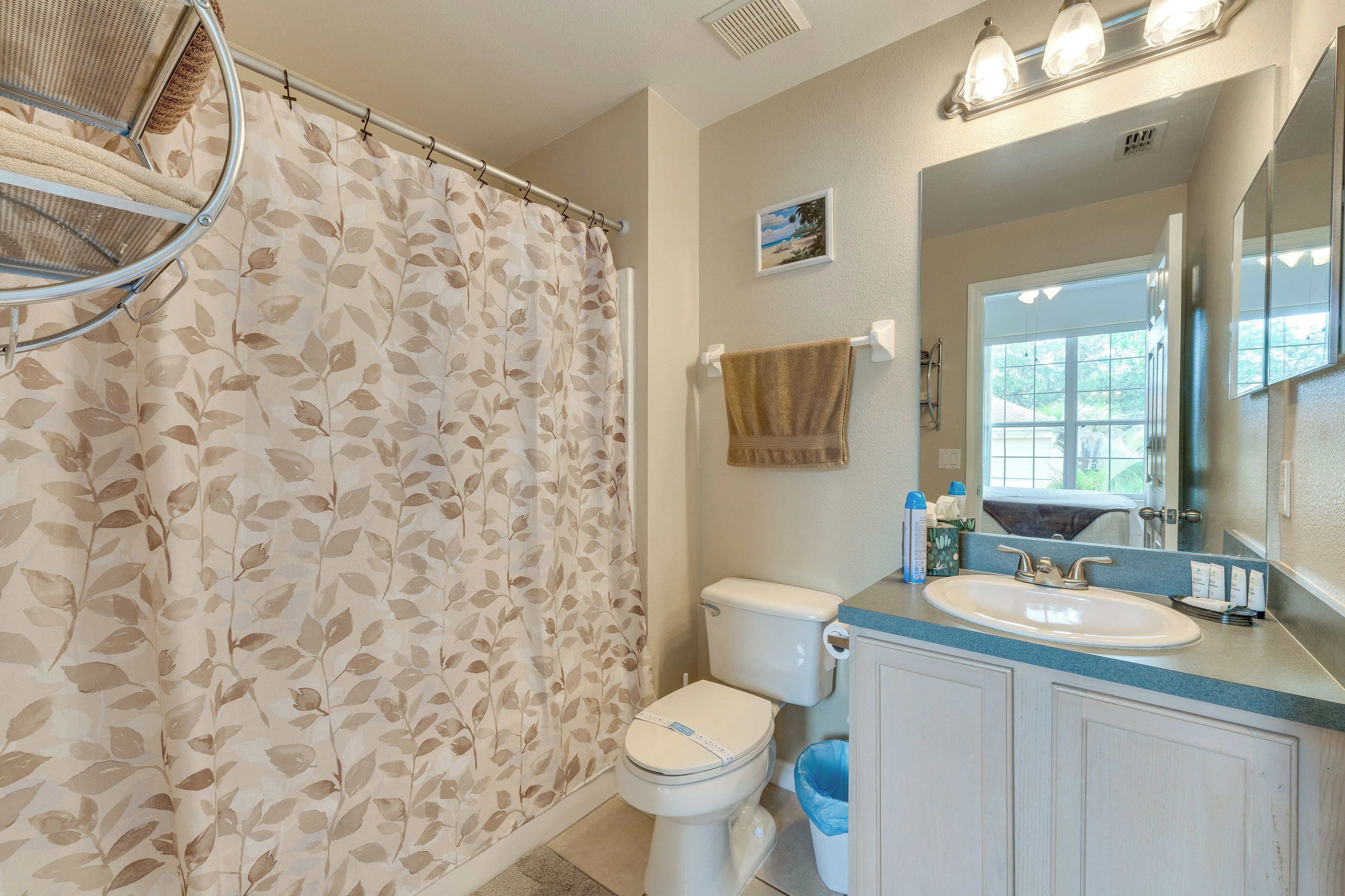 Une salle de bain avec un rideau de douche, des toilettes, un lavabo et un miroir.