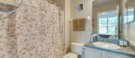Une salle de bain avec un rideau de douche, des toilettes, un lavabo et un miroir.