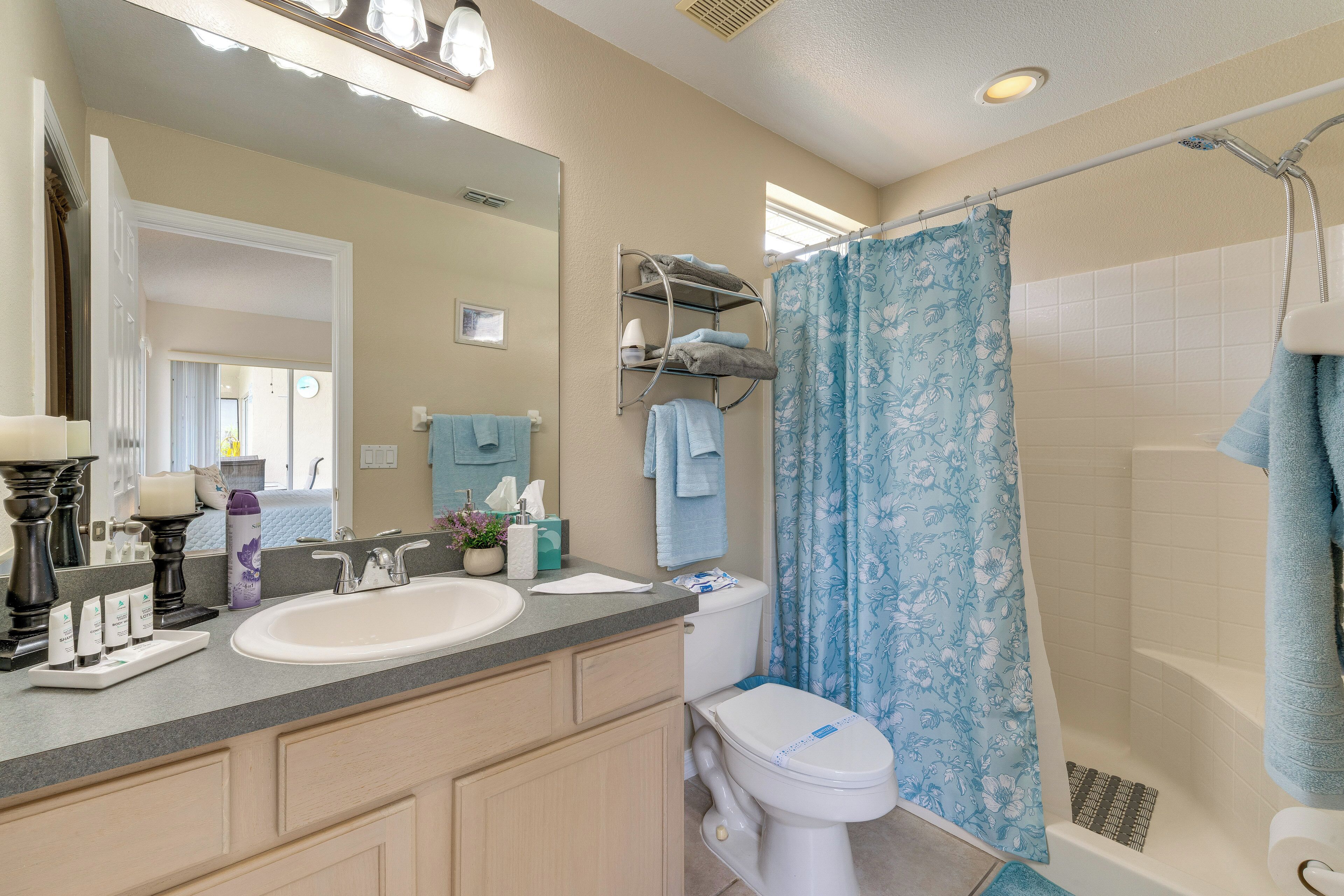 A bathroom with a sink, toilet, shower, and a mirror.