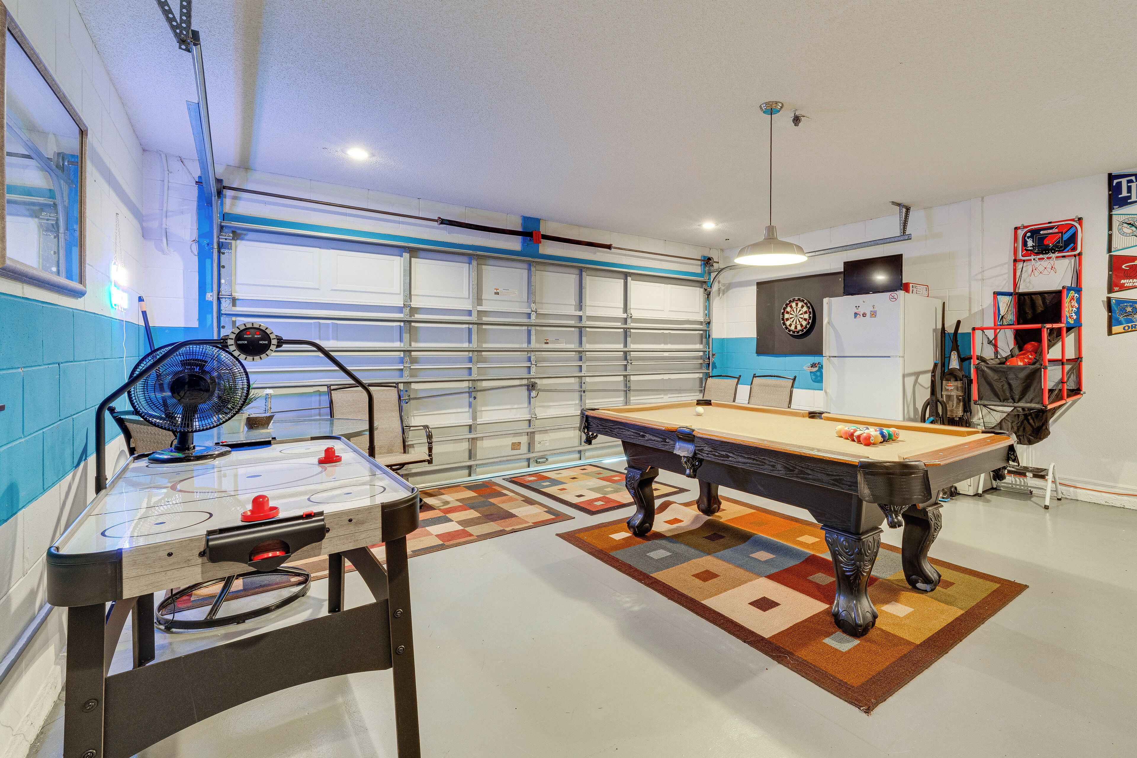 Une pièce équipée d’une table de billard, d’un ventilateur, d’un jeu de fléchettes et d’un réfrigérateur.
