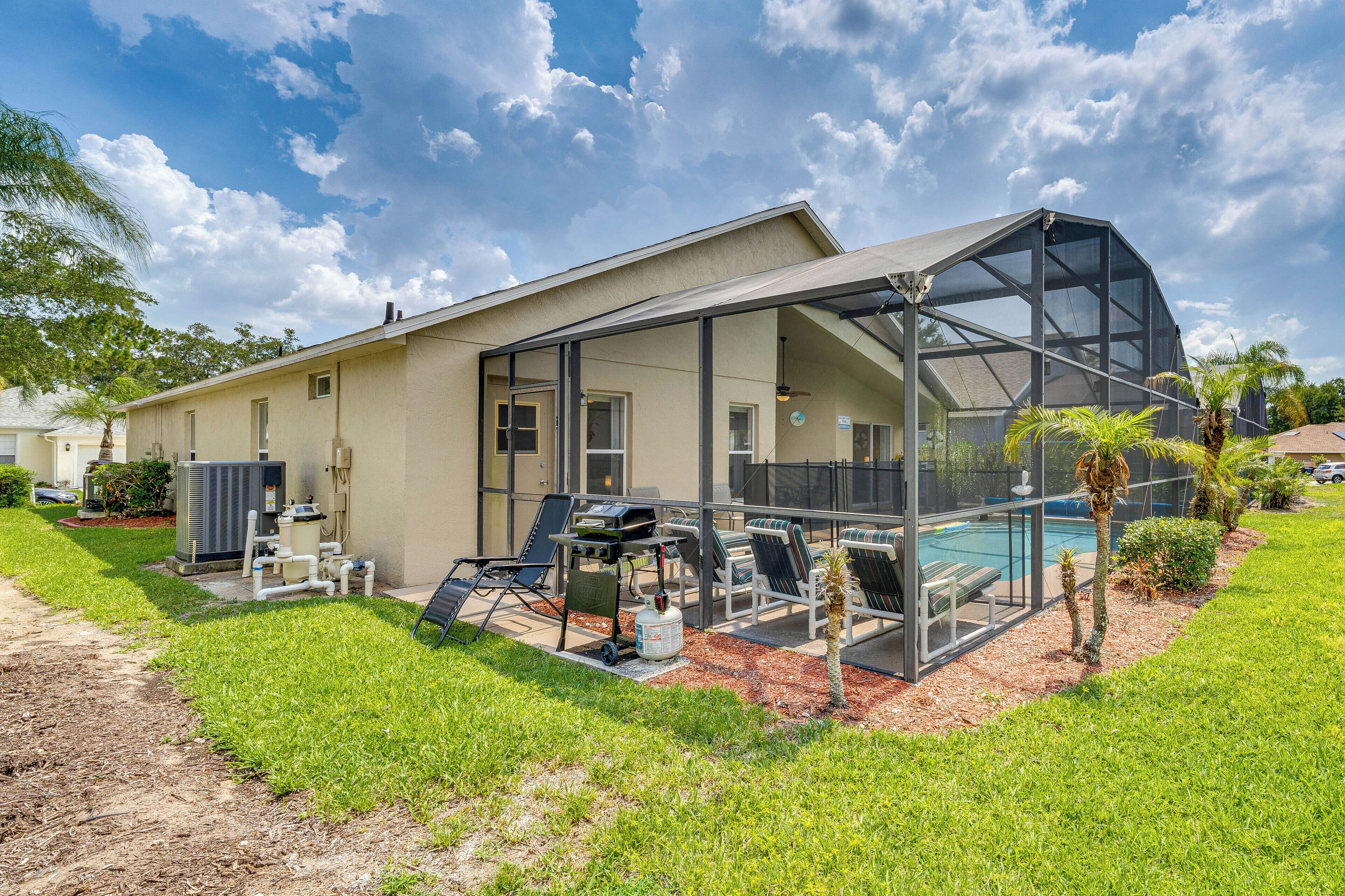 A house with a large glass-enclosed patio, a swimming pool, and a well-maintained lawn.