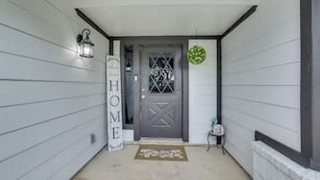 A house entrance with a gray door, a welcome mat, a lantern, and a sign that says 'WELCOME HOME'.