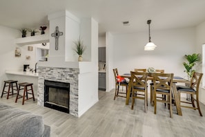 A modern living room with a fireplace, a dining area with wooden chairs, and a kitchen in the background. - 3 Mi to Seaworld! Cozy Family Home w/ Patio (San Antonio)