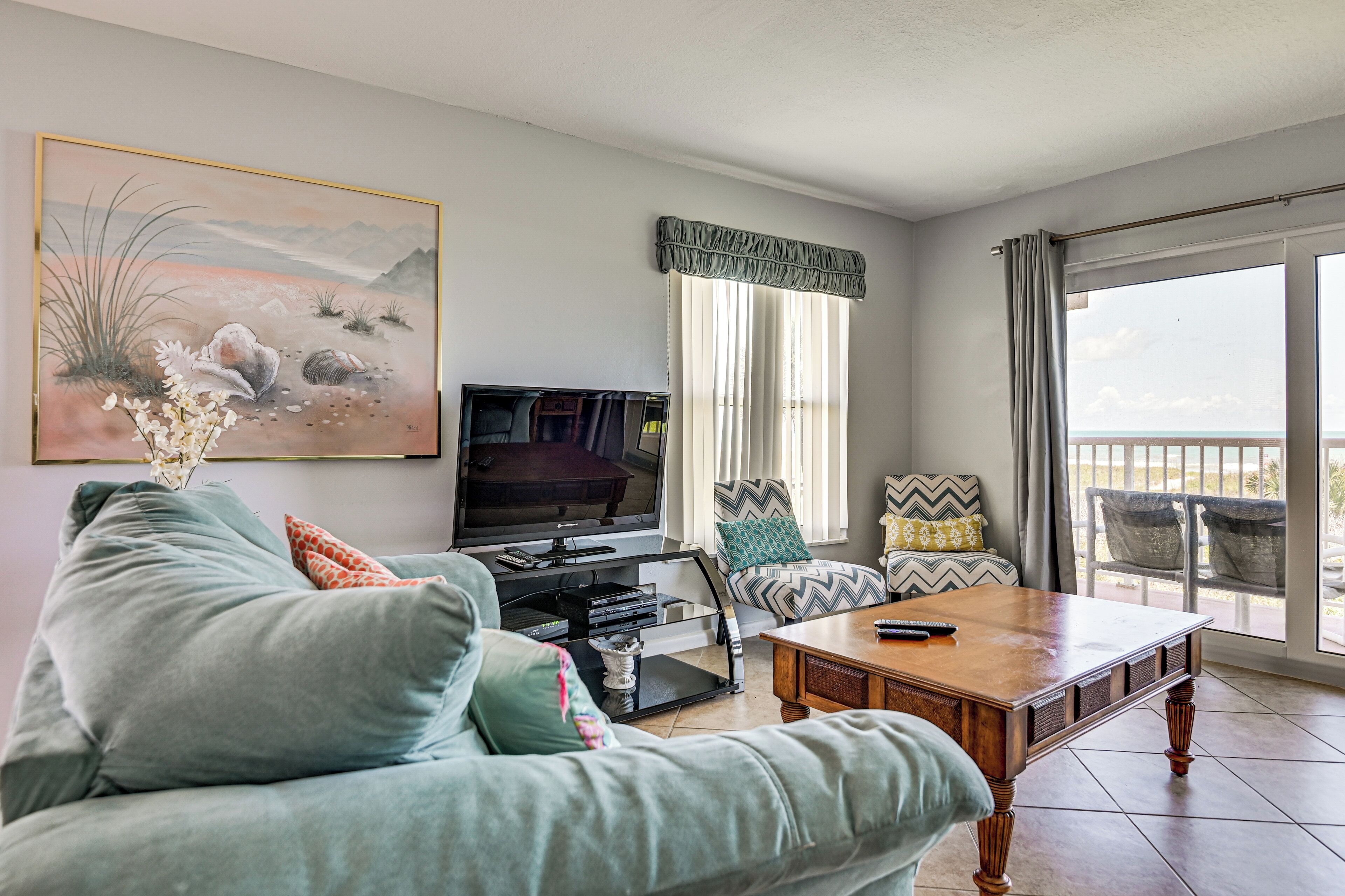 A living room with a sofa, a coffee table, a TV, and a painting on the wall.