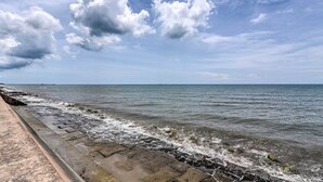 A coastal walkway with a stone barrier and ocean waves. - Gorgeous Condo Close to Beach and Local Favs (Galveston)