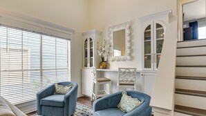 A living room with two blue armchairs, a white cabinet, and a mirror. - Gorgeous Condo Close to Beach and Local Favs (Galveston)
