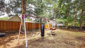 A backyard with a swing set, a wooden fence, and a tree. - Extended-stay Home/office, 8 Mi to Dtwn Denver (Lakewood)