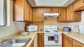Una cocina con armarios de madera, microondas, estufa y tostadora.