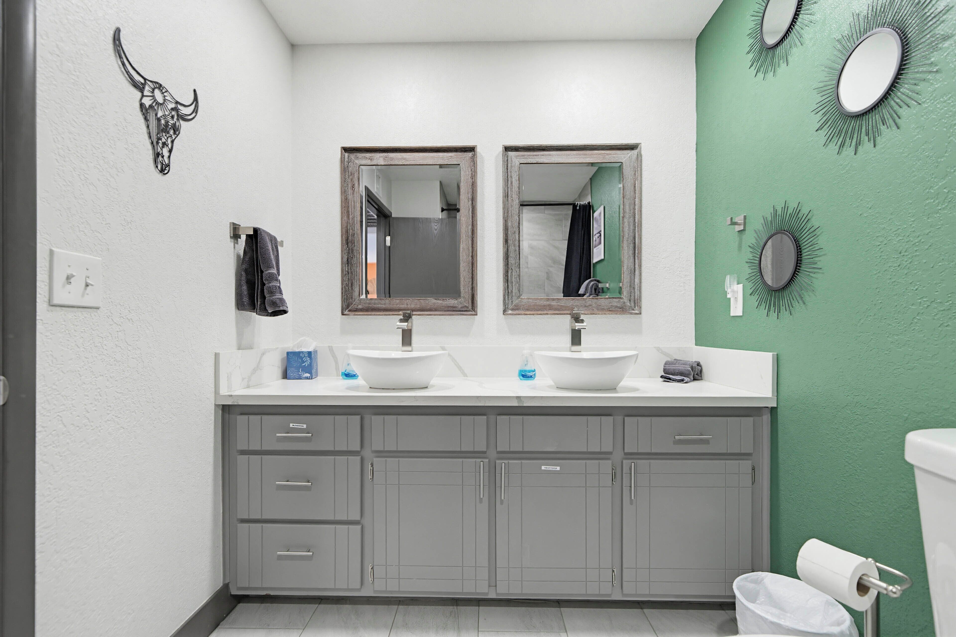 A bathroom with two sinks, a mirror, a towel rack, and a toilet.