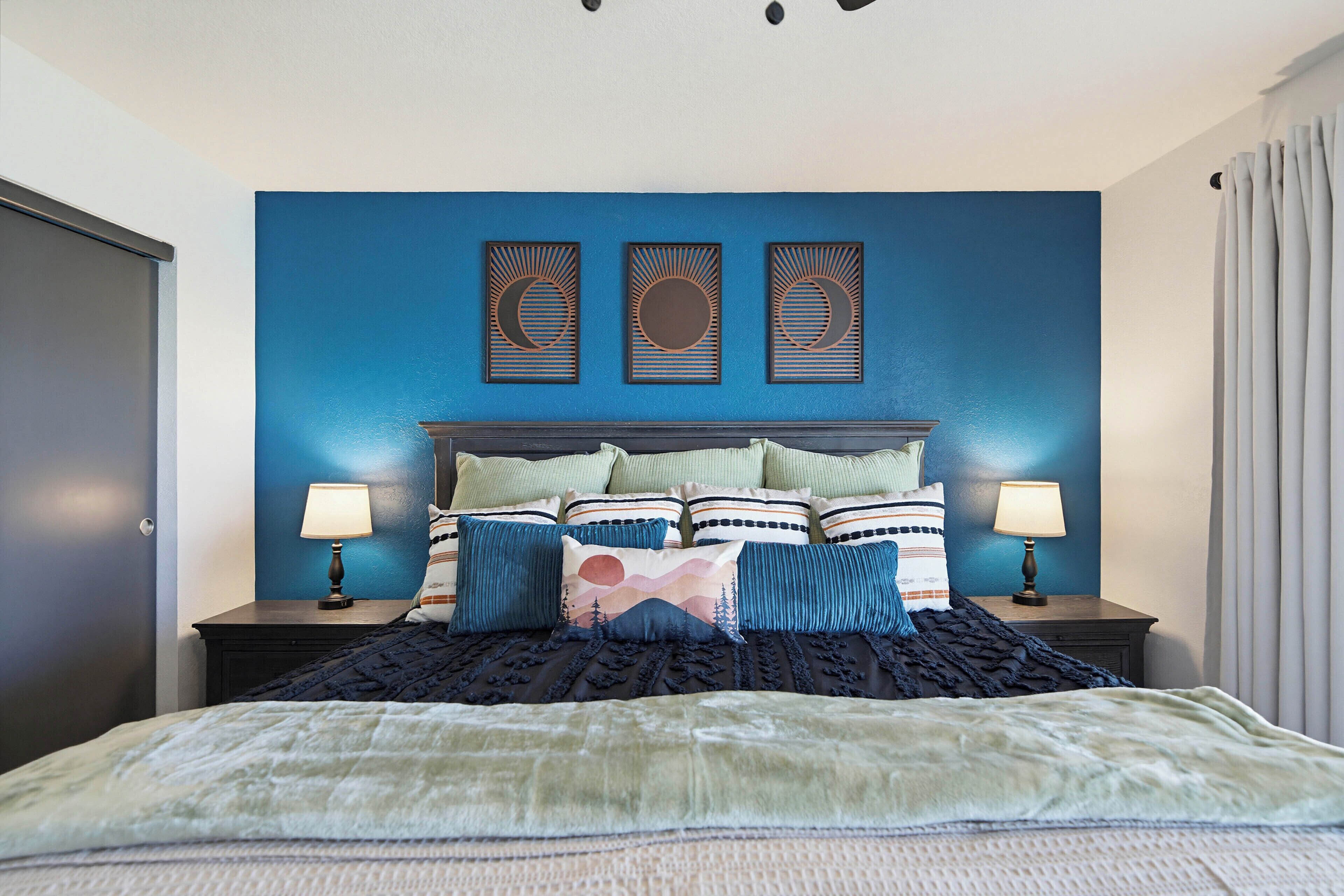 Un dormitorio con una cama, dos mesitas de noche, un cabecero y tres paneles decorativos en la pared.