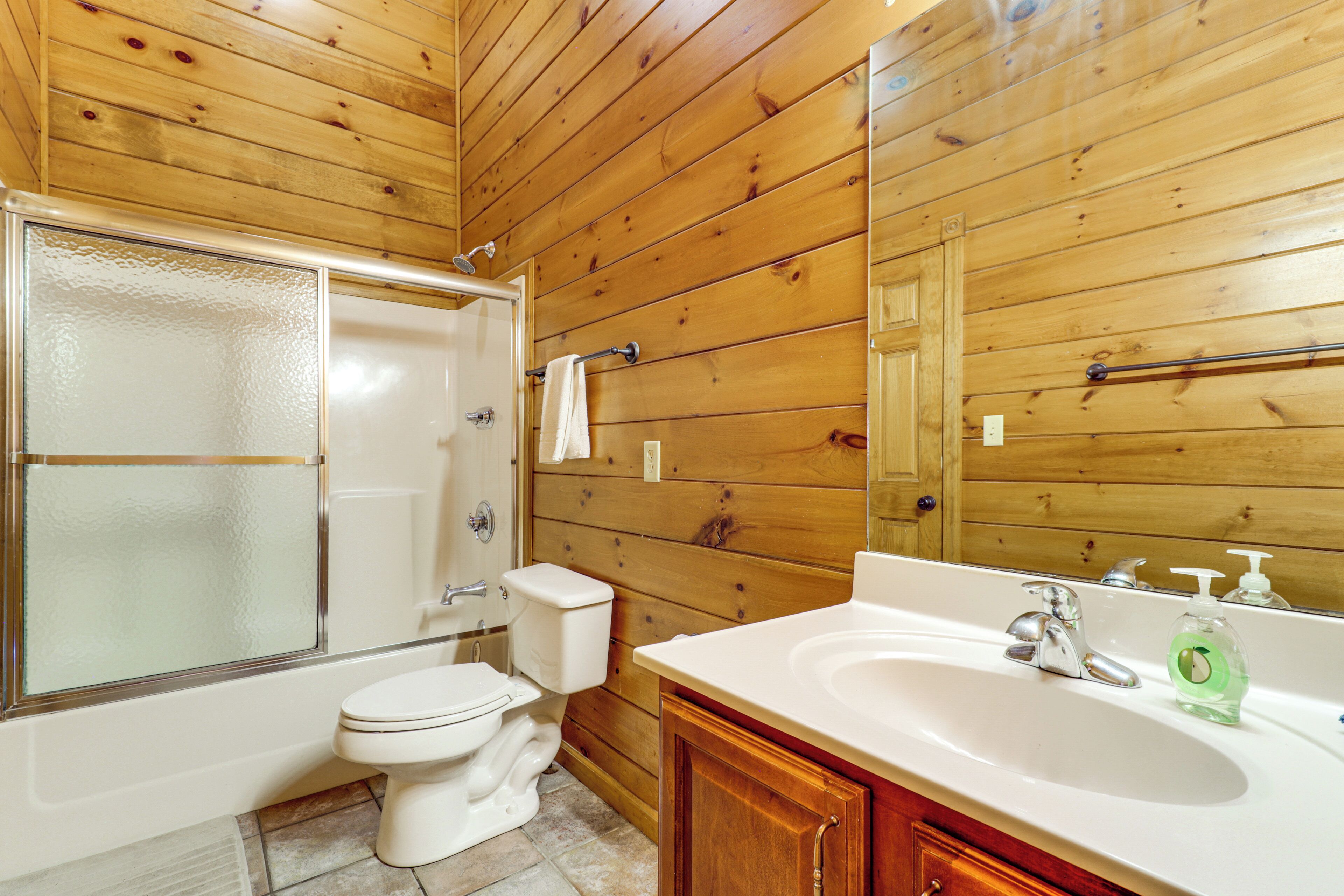 Un baño con paneles de madera, una bañera, un inodoro y un lavabo.