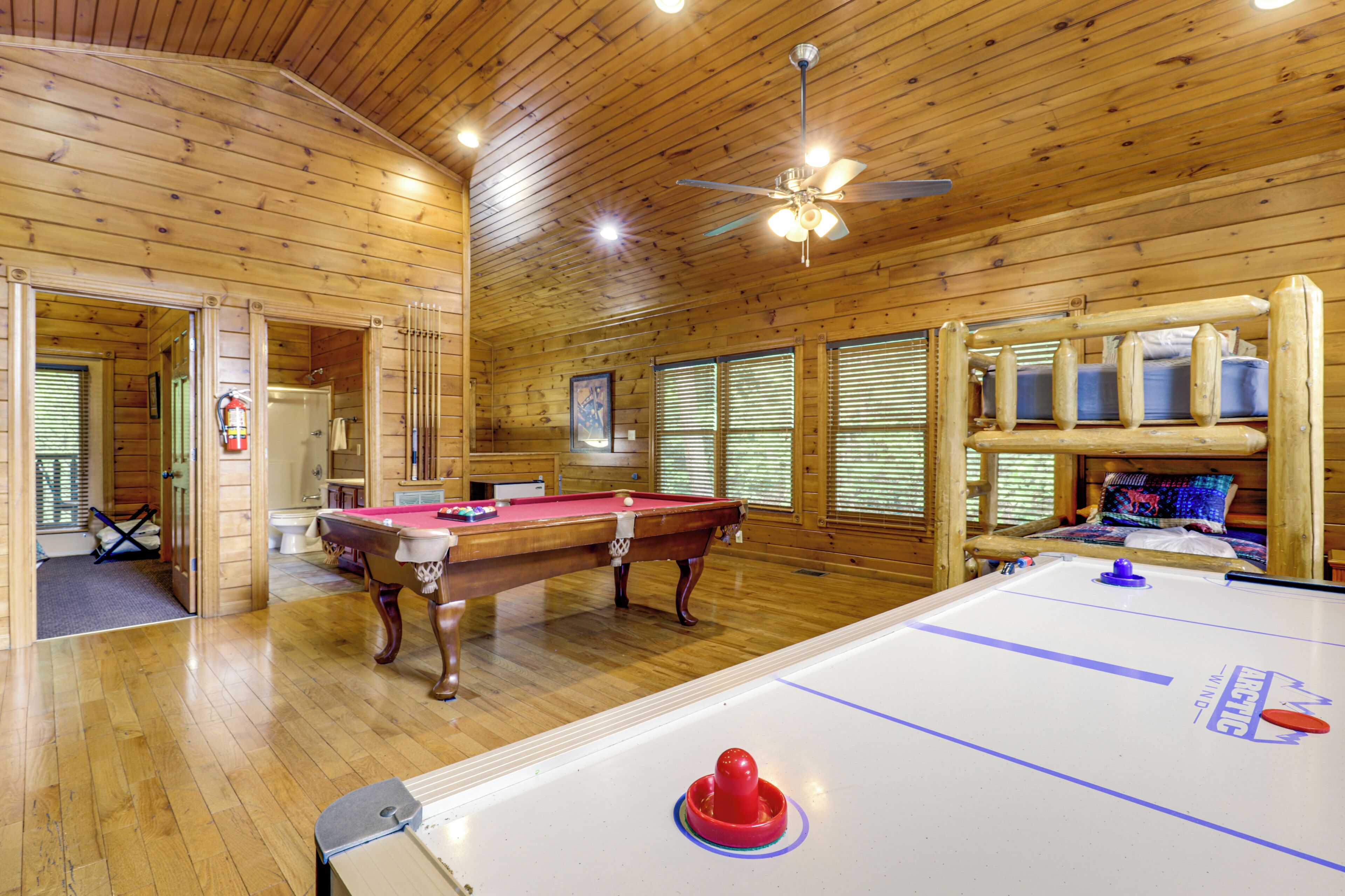 En inredning med träpaneler, ett biljardbord, ett shuffleboard-bord och en takfläkt.