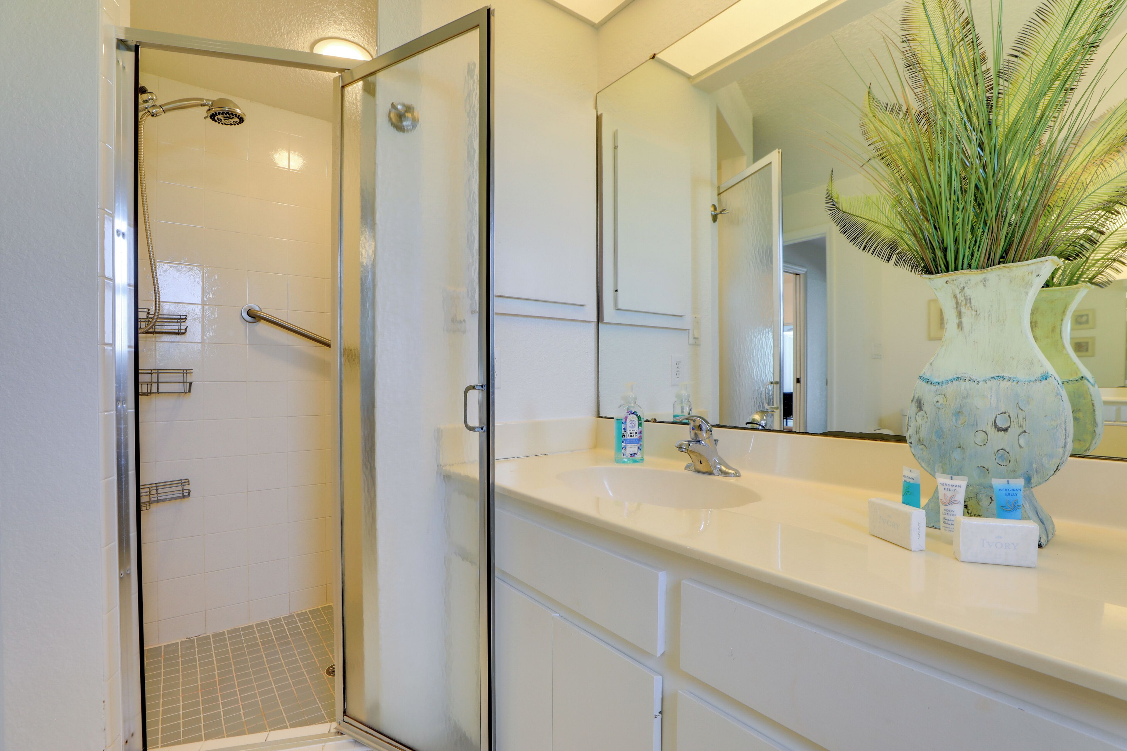 A bathroom with a shower, a sink, and a mirror.