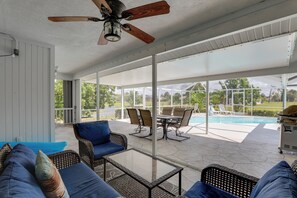 A covered patio with outdoor furniture, a ceiling fan, and a view of a swimming pool. - Patio & Grill! Canalfront Rotonda West Golf Escape (Rotonda West)