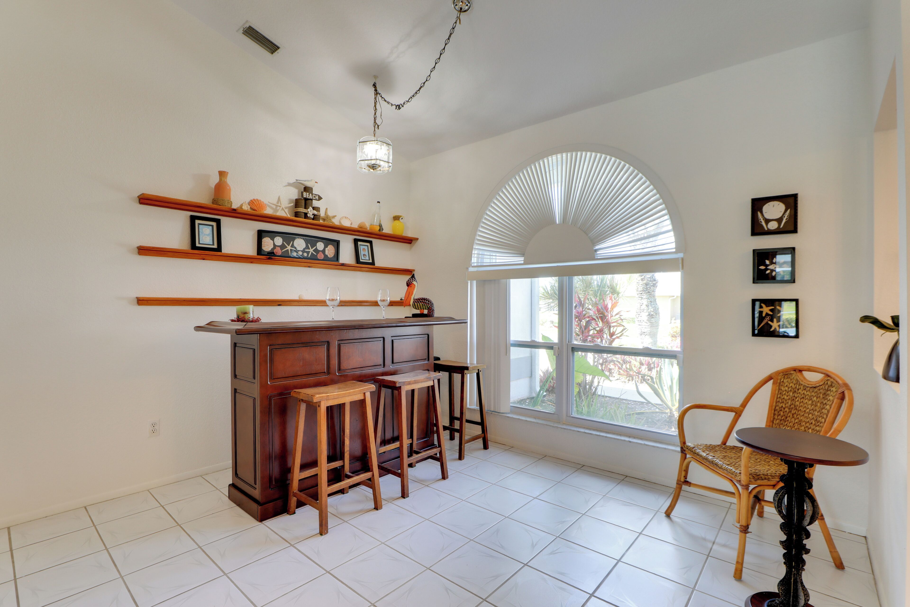 A kitchen with a bar area, wooden stools, a chair, and a table.
