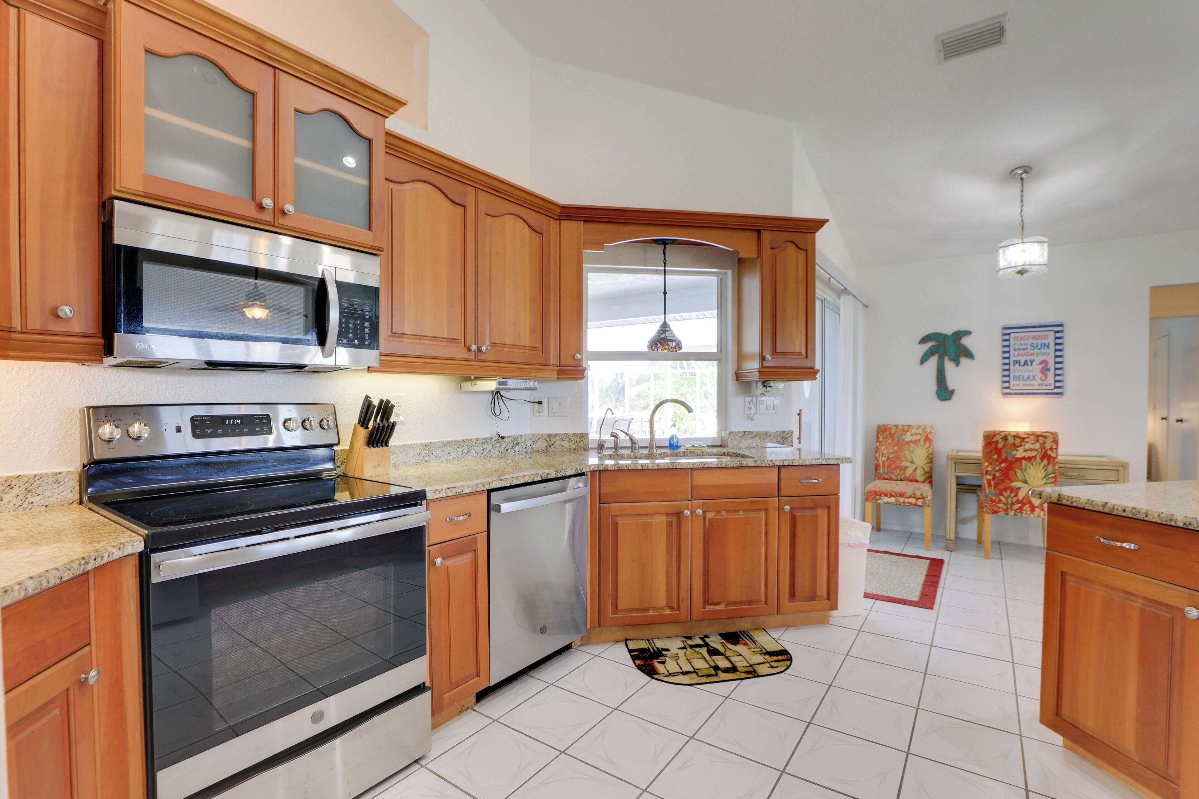 A kitchen with wooden cabinets, stainless steel appliances, a granite countertop, and a dining area with chairs.