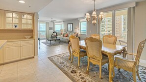 A spacious living area with a dining table, chairs, and a view of the cityscape. - Beachfront Condo w/ Wide Balcony in Marco Island! (Marco Island)