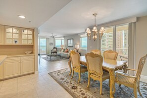 A spacious living area with a dining table, chairs, and a view of the cityscape. - Beachfront Condo w/ Wide Balcony in Marco Island! (Marco Island)