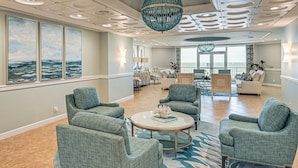 A spacious living area with a large window, a chandelier, and multiple seating options. - Beachfront Condo w/ Wide Balcony in Marco Island! (Marco Island)