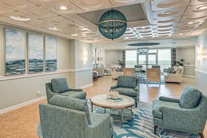 A spacious living area with a large window, a chandelier, and a view of the ocean. - Beachfront Condo w/ Wide Balcony in Marco Island! (Marco Island)