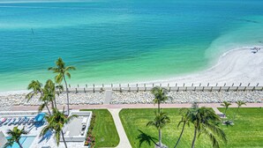 A beach resort with a pool, palm trees, and a view of the ocean. - Beachfront Condo w/ Wide Balcony in Marco Island! (Marco Island)