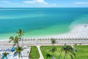 A beach resort with a swimming pool, palm trees, and a view of the ocean. - Beachfront Condo w/ Wide Balcony in Marco Island! (Marco Island)