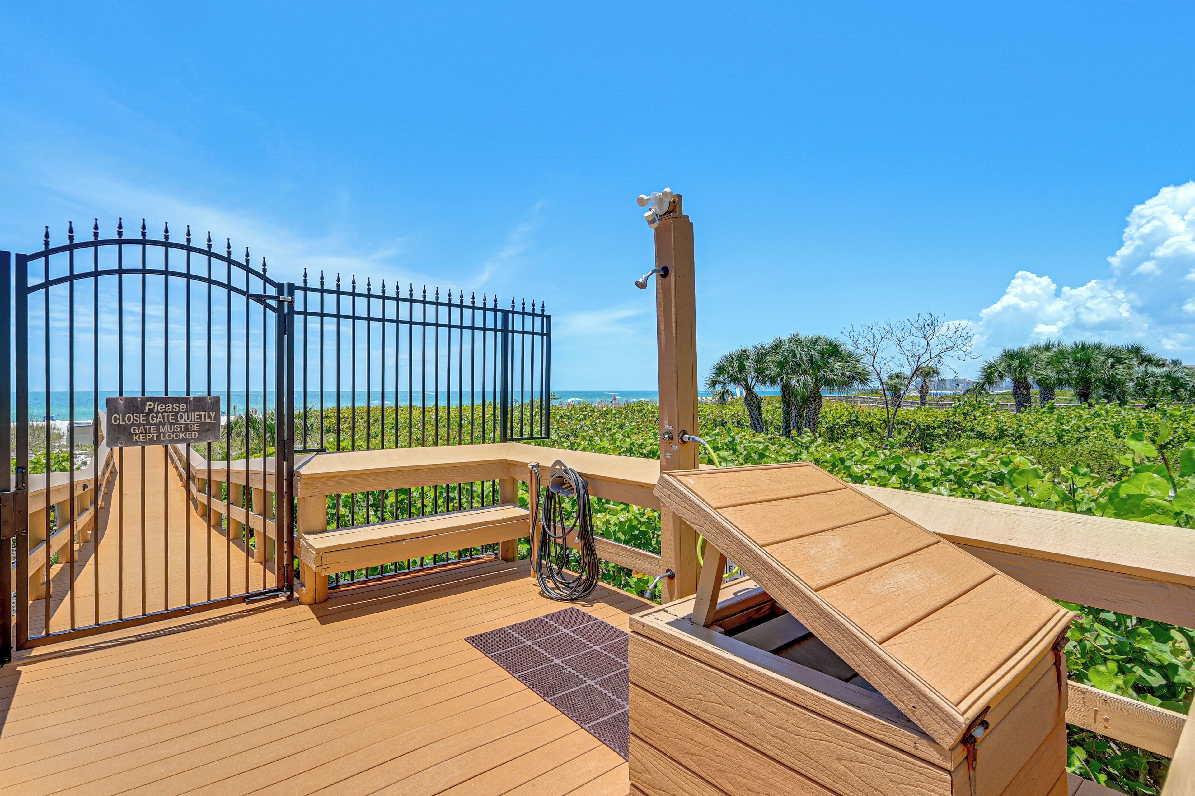 A wooden deck with a gate, a bench, and a view of the sea.