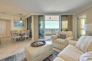 Ein Wohnzimmer mit Sofa, Hocker und Essbereich mit Stühlen und Tisch.