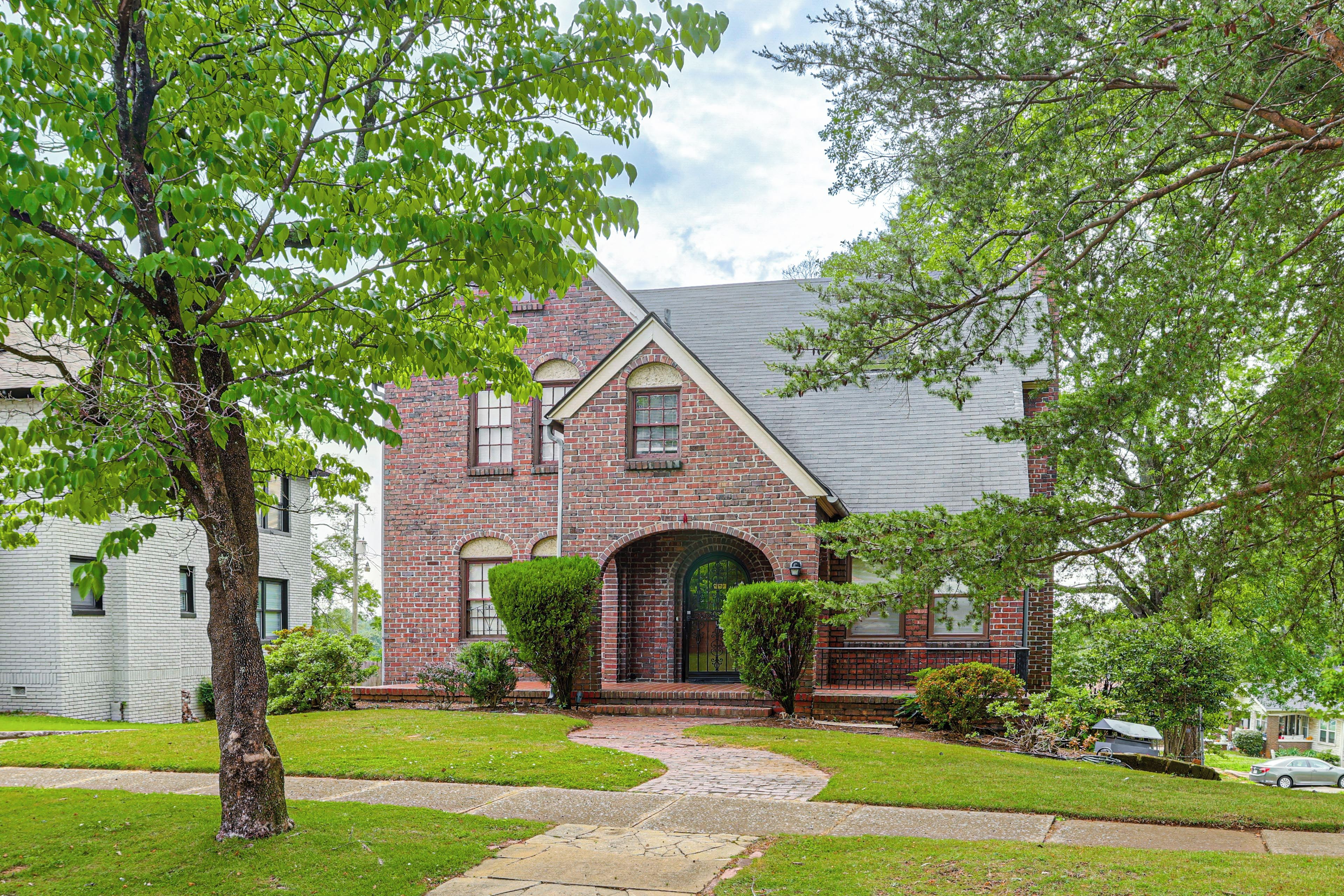 A brick house with a central entrance, a paved driveway, and a lawn.