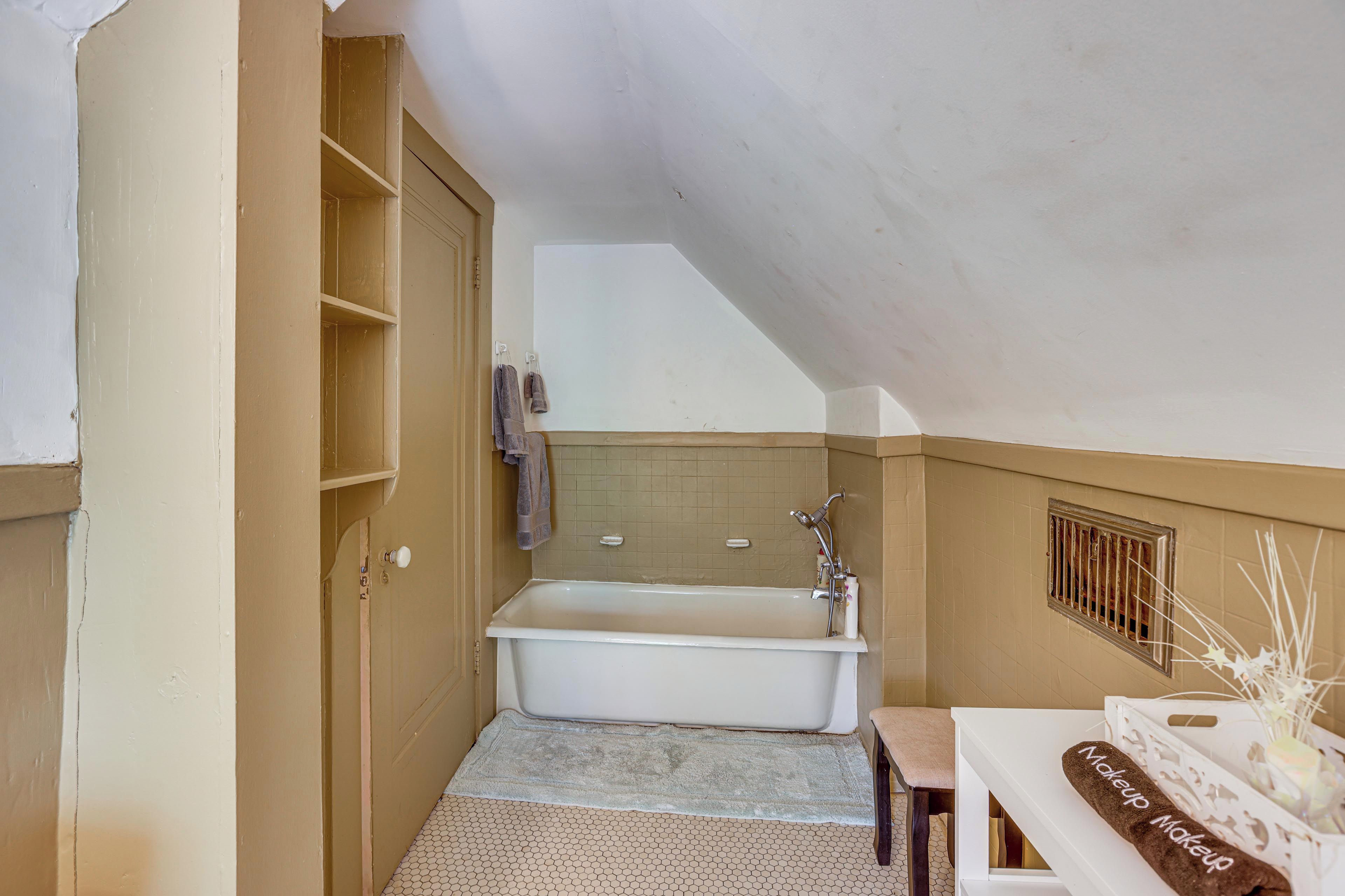 Un baño pequeño y compacto con bañera, tocador con una toalla y ventana.