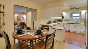 A kitchen with white cabinets, a dining table with chairs, and a small island with a sink. - 13 Miles to Arrowhead Stadium! Bbq-ready Home Base (Kansas City)