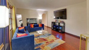 A living room with a sofa set, a coffee table, a flat-screen TV, and a bookshelf. - 13 Miles to Arrowhead Stadium! Bbq-ready Home Base (Kansas City)