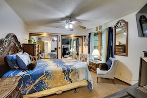 A bedroom with a bed, a ceiling fan, a chair, a dresser, and a television.