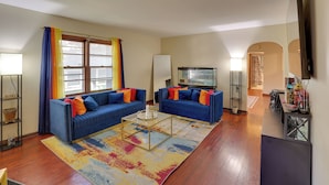 A living room with two blue sofas, a coffee table, a TV, and a bookshelf. - 13 Miles to Arrowhead Stadium! Bbq-ready Home Base (Kansas City)