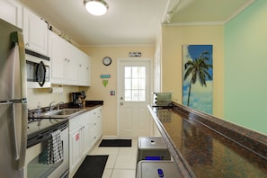 A compact kitchen with white cabinets, a stainless steel refrigerator, a microwave, and a coffee maker. - Bikes Provided! Central Condo w/ Pool in Key West (Key West)