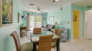 A dining area with wicker chairs, a glass-top table, and a ceiling fan. - Bikes Provided! Central Condo w/ Pool in Key West (Key West)