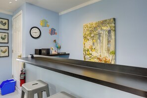Ein Zimmer mit blauer Wand, einer Uhr, einem Gemälde, einem Regal mit einem Schild und einem Feuerlöscher.